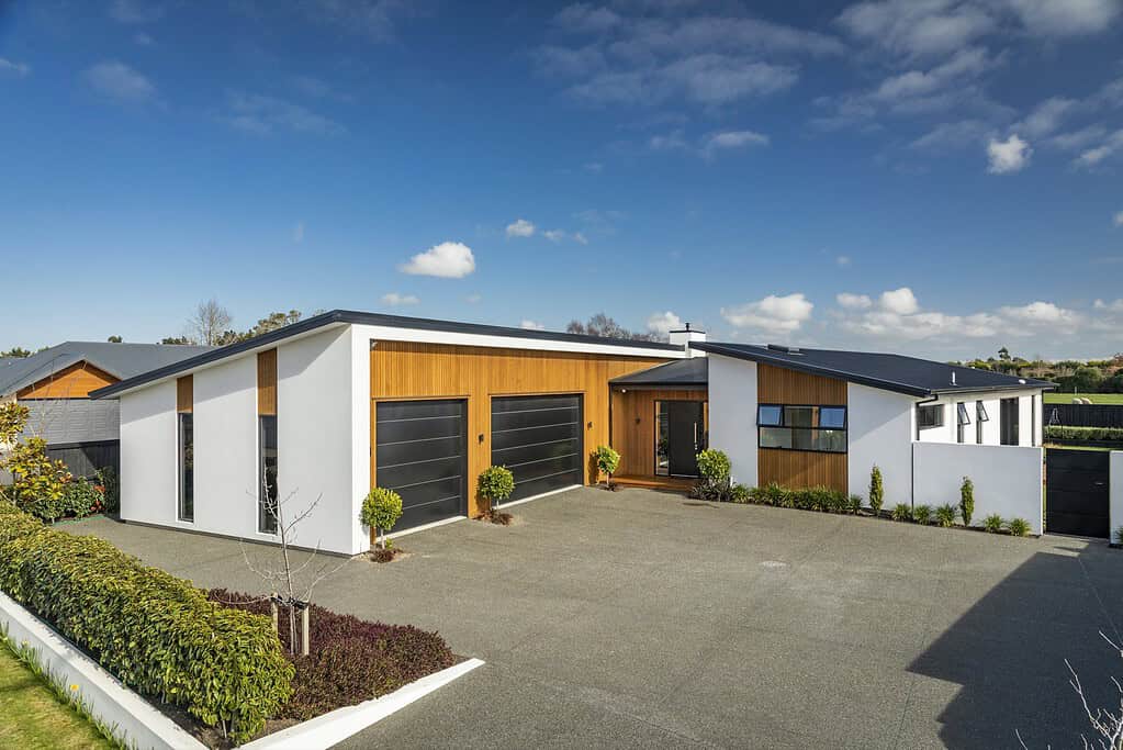 Single-level Coughlan Homes build in Canterbury with cedar garage doors and a wide driveway.