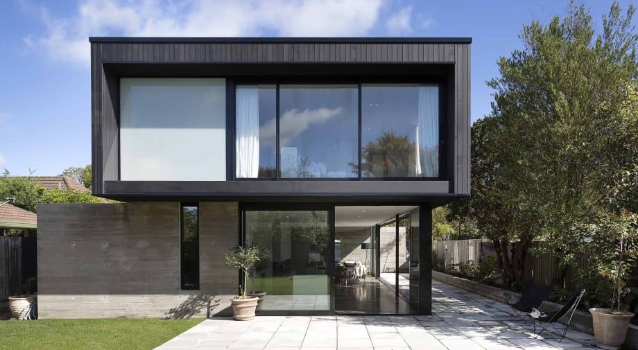 Dark-stained timber and glass architectural home in Christchurch, rear elevation onto lawn.