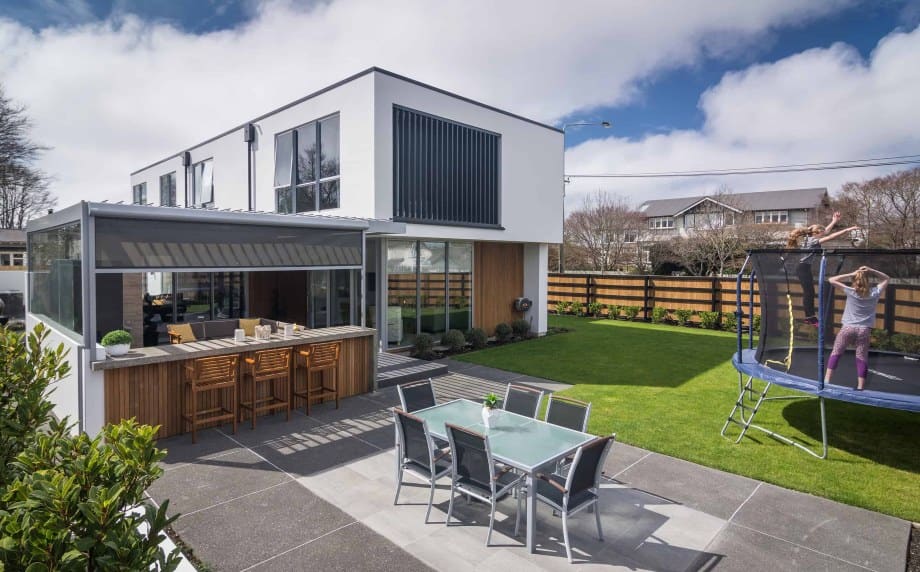 Two-storey Coughlan Homes build in Christchurch with covered outdoor bar, paved terrace and lawn.